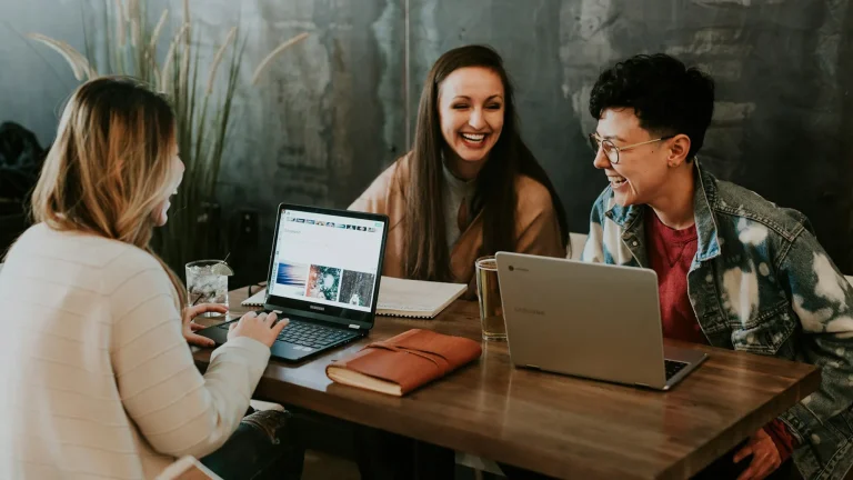 people working at a desk together on laptops