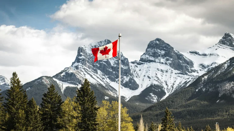 canada flag in front of the rocky mountains